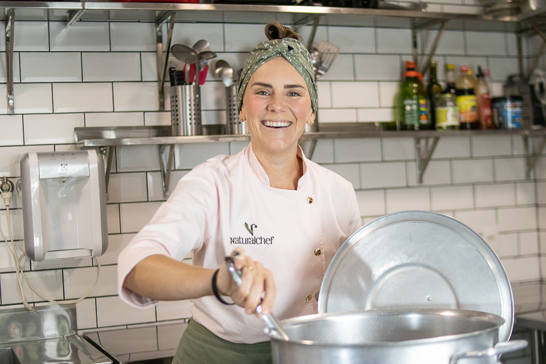 Chef Gabi sorrindo ao lado da panela